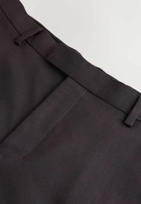Ciemnobordowe spodnie wykonane z teksturowanej tkaniny, z płaskim przodem, zszywaną talią i szlufkami na pasek. Minimalistyczny design bez widocznych kieszeni.