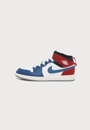 Basket montante Nike Air Jordan en blanc, bleu, rouge et noir avec des lacets blancs et une semelle en caoutchouc, vue de côté.