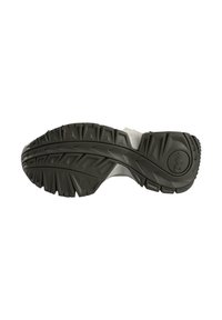 Black rubber shoe sole with deep treads for traction, featuring angular patterns and a circular logo on the heel area.