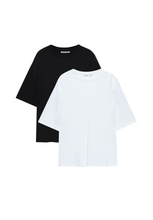 To ensfarvede, oversized T-shirts med rund halsudskæring, den ene sort bag den hvide, lagt fladt på en hvid baggrund.