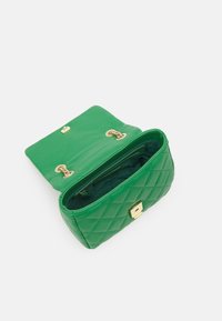 Zelená prošívaná kožená kabelka se zlatým zapínáním, s hladkým vnitřkem a obdélníkovým tvarem. Otevřený pohled ukazující vnitřní přihrádky.