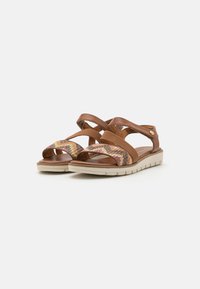 Sandali in pelle marrone con cinghie incrociate e un motivo tessuto multicolore. Suola imbottita e suola in gomma chiara con trazione.