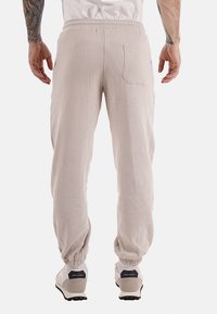 Pantalones de pana beige con un corte relajado y cinturilla elástica. Cuentan con un bolsillo trasero y puños elásticos en los tobillos.