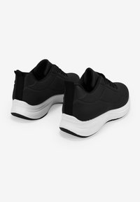 Zapatillas deportivas negras con parte superior de textil suave, entresuela blanca, acentos texturizados y un tab en el talón para facilitar su uso.