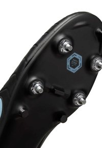 Black soccer cleat sole with six metal studs and an "ANTI CLOG" label in blue hexagon. Features a textured edge and smooth surface.