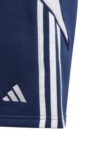 Navy blue athletic shorts made of soft fabric, featuring three white vertical stripes and an embroidered logo in the lower corner.
