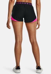Pantalones cortos deportivos negros con llamativos acentos laterales en rosa y cinturilla con logotipo. El material parece suave y ligero, adecuado para ropa activa.