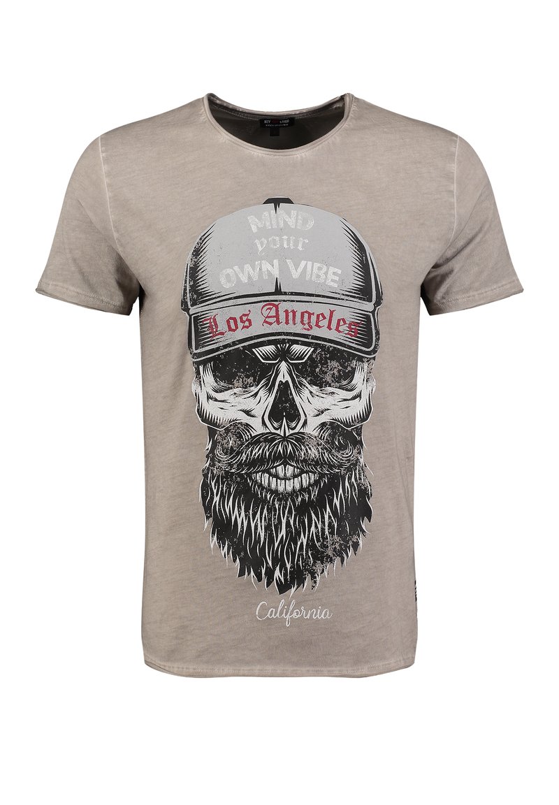 Camiseta de algodón beige con un gráfico de calavera negra que lleva barba y gorra, con el texto "Cuida tu propia vibra" y "Los Ángeles."