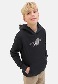 Hoodie noir avec une poche kangourou, présentant un logo graphique en blanc et des accents colorés. Manches longues avec une capuche spacieuse.