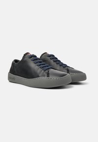Sneaker in pelle nera con lacci blu, punta arrotondata e suola in gomma grigia con dettagli di cucitura sui lati.