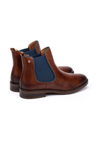 Pair of brown leather Chelsea boots with blue elastic side panels and low stacked heels, shown on white background.