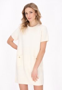 Vestito a maniche corte color crema con tessuto testurizzato, scollatura rotonda e due tasche frontali con bottoni dorati.
