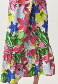 Robe midi florale avec un mélange de fleurs roses, bleues et vertes sur un fond clair, dotée d'un ourlet froncé et d'un tissu léger.