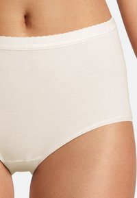 Slip beige in cotone con vita alta, caratterizzato da un delicato bordo scallop lungo l'elastico e una texture liscia.