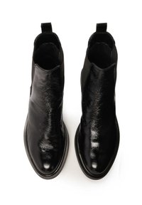 Botas negras de tobillo con un acabado de cuero brillante, puntera redonda, paneles laterales elásticos y tiradores en el talón. Suela plana de goma.