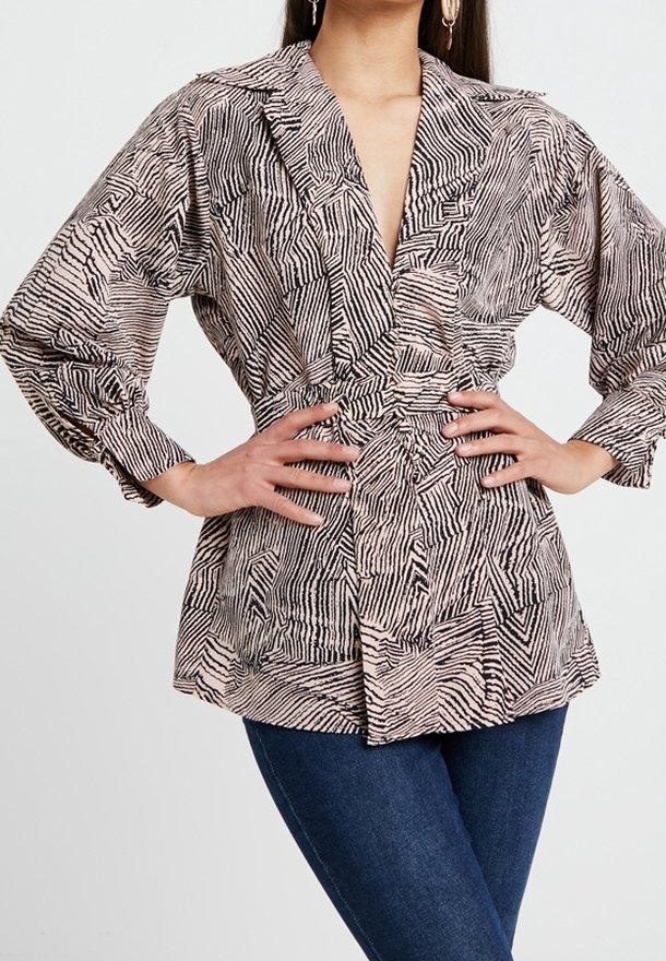 Blouse légère à motifs rose et noir, avec un profond décolleté en V, des manches longues, une taille cintrée et un col structuré.