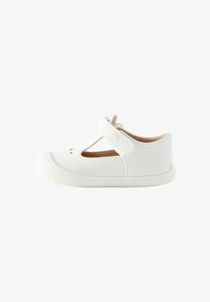 Zapato Mary Jane de cuero blanco con tira en T, punta redonda y suela de goma texturizada; presenta detalles perforados y correa ajustable de Velcro.