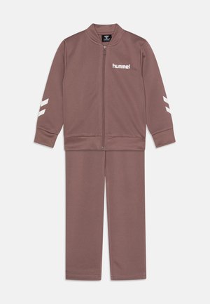 Brun atletisk træningsdragt lavet af glat stof, der inkluderer en jakke med lynlås med hvidt logo og striber, samt matchende bukser med elastiske manchetter.