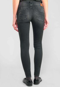 Dunne zwarte spijkerbroeken van denim met een vervaagde textuur. Voorzien van twee achterzakken en een klein leren etiket aan de tailleband.