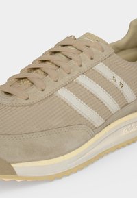 Baskets Adidas SL 72 beige en tissu texturé, détails en suède, bandes blanches, lacets beiges et semelle marron clair rainurée.