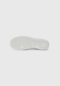 Sole di sneaker bianca con motivi a trama circolare e logo Nike impresso al centro, mostrata su uno sfondo bianco uniforme.
