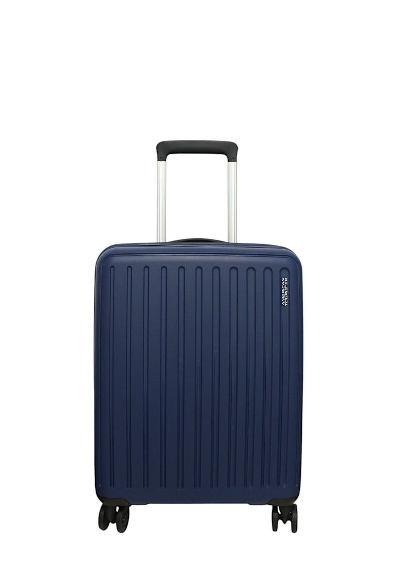 Valigia rigida blu navy con texture a coste verticali, manico telescopico argentato e quattro ruote nere per la mobilità.