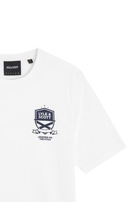 Hvid bomulds t-shirt med et marineblåt grafikdesign, der inkluderer "LYLE & SCOTT" og "LEGENDS ON THE PITCH" inden for en skjoldmotif.