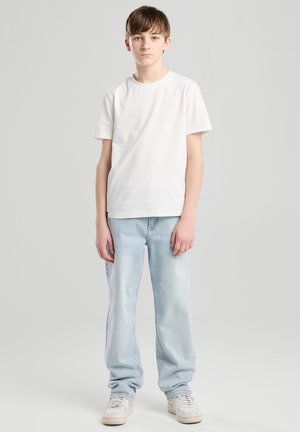 White cotton t-shirt paired with light blue denim jeans. Casual fit, straight leg, with white sneakers completing the outfit.