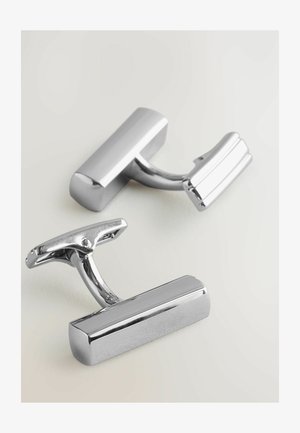 Stříbrné manžetové knoflíky s lesklým povrchem, ve tvaru obdélníků a s zakřiveným závěsem pro bezpečné uzavření.