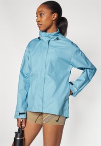 Giacca impermeabile blu con colletto alto, zip frontale e cordini regolabili. Presenta dettagli neri sui polsini e un design elegante.