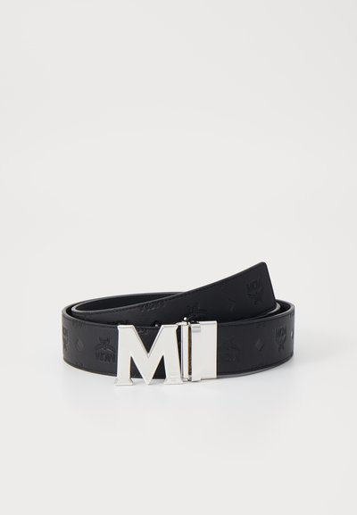 Black leather belt with embossed patterns, featuring a silver metal buckle with "MI" design. Smooth texture, rounded edges.