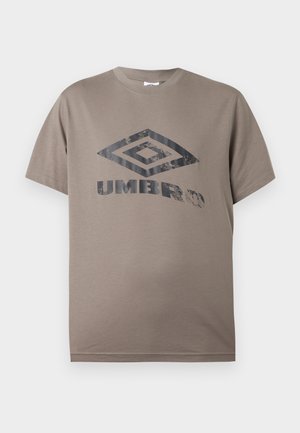 Καφέ-γκρι κοντομάνικο T-shirt με στρογγυλή λαιμόκοψη και φθαρμένο μαύρο λογότυπο Umbro στο κέντρο του στήθους, πάνω σε απλό λευκό φόντο.