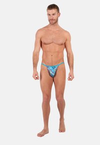 Männlicher Tanga in leuchtendem Blau mit Paisleymuster. Verfügt über dünne Träger, einen niedrigen Schnitt und ein strukturiertes Material.