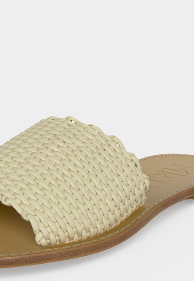 Μπεζ σανδάλι slide με φαρδιά πλεκτή λουρίδα και επίπεδη καφέ σόλα, που δείχνει πλεκτή υφή και ραμμένες άκρες.
