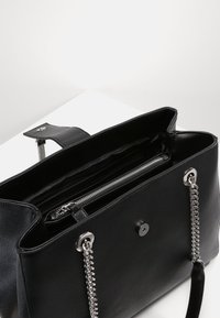 Borsa tote nera in pelle con tracolle in catena argentata, finitura testurizzata, tasca con zip interna e chiusura magnetica. L'interno è foderato in tessuto nero.