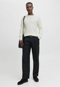 Pull à rayures vert clair à manches longues, pantalon noir ajusté, sac noir et chaussures noires. Texture lisse avec une coupe décontractée.