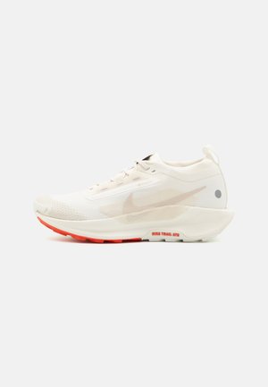 Weißer Sportschuh mit einem strukturierten Mesh-Obermaterial, reflektierenden Akzenten und einer segmentierten roten Außensohle. Verfügt über ein Schnürdesign und einen gepolsterten Kragen.