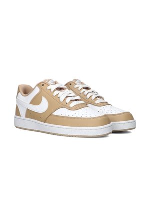 Een paar lage sneakers in beige en wit met witte veters en geperforeerd teenstuk, naast elkaar weergegeven op een witte achtergrond.