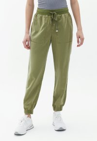 Olivgrüne Hose mit elastischem Bund und Zugband, zwei Fronttaschen, schmal zulaufenden Bündchen und einem glatten, leichten Stoff.