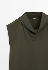Top senza maniche verde oliva con scollo a V e colletto piegato, realizzato in tessuto liscio. Presenta linee pulite e dettagli di cucitura minimi.
