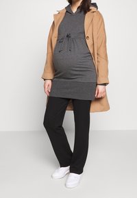 Šedé šaty s kapucí a stahováním v pase, béžový kabát, černé kalhoty a bílé tenisky. Měkká látka, volný střih, vhodné pro těhotenské nošení.