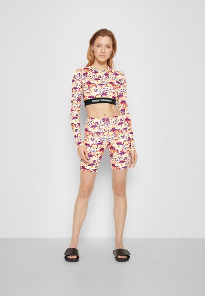 Conjunto de roupas de desporto com padrão floral, apresentando uma t-shirt cropped de manga longa com uma faixa preta na cintura e calções a condizer, confeccionados em tecido elástico.