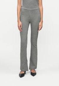 Hvid- og sort houndstooth mønster flared bukser med høj talje, der har en glat tekstur og udskæringer i kanten.