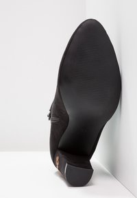 Stivaletto in suede nero con zip laterale, suola in gomma testurizzata, tacco basso a blocco e n. 37 marchiato sulla suola.