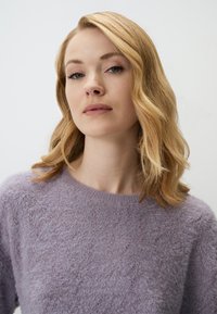 Lichtpaars gebreid sweater met een wollige textuur en subtiel patroon. Ronde hals, iets oversized pasvorm en zachte uitstraling.