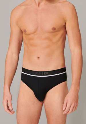 Zwarte korte onderbroek met een rekbare tailleband, voorzien van een contrasterende witte streep en logo. Glad materiaal met een aansluitende pasvorm.