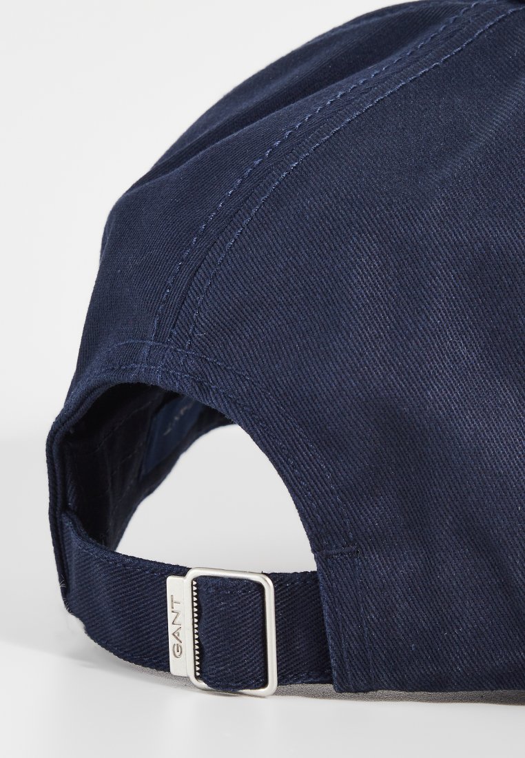 Mörkblå keps i bomull med en strukturerad design, böjd skärm och justerbar rem med metallhårdvara för storleksjustering.