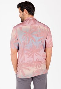 Kurzarmhemd in Hellrosa mit Palmenmuster; weicher Stoff, lockere Passform und ein sanfter Farbverlauf von Rosa zu Blau.