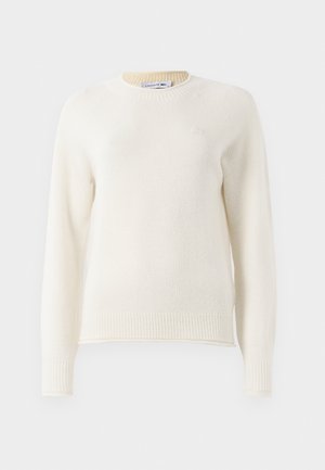 Pull en maille blanc cassé à manches longues avec des poignets et un ourlet côtelés, col rond, et petit logo brodé sur la poitrine.