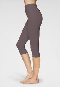 Violetinės capri tipo legging'os su aukštu juosmeniu, lygiu paviršiumi ir prigludusia forma, siekiančios pusę blauzdų, puikiai tinkančios aktyviam sportui.